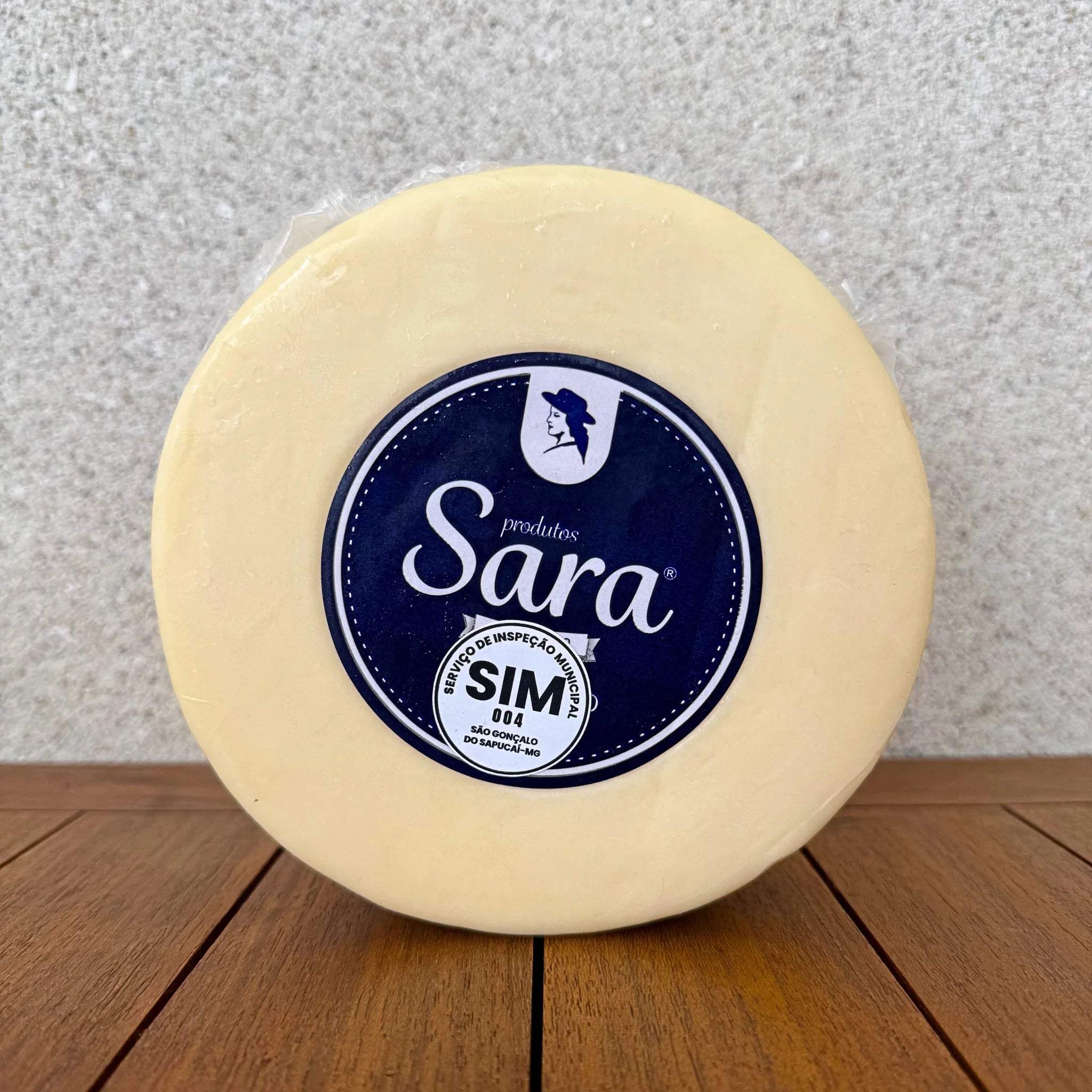 A round wheel of artisanal Sara cheese on a wooden surface.