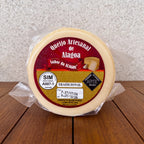 Artisanal Alagoa cheese wheel wrapped in plastic on a wooden surface.